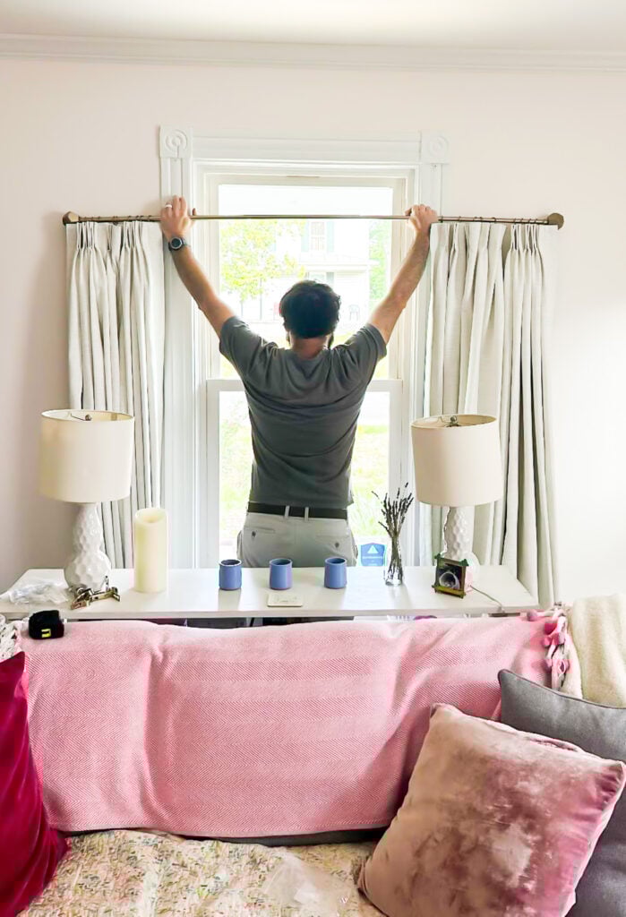 man hoisting up curtain rod with new TwoPages drapes attached.